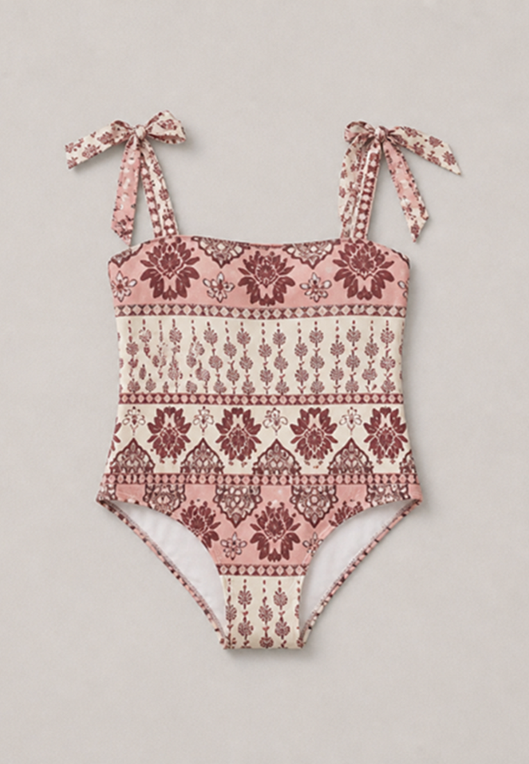 Coral Secret one-piece swimsuit with tie shoulder straps, featuring a bohemian-style geometric and floral pattern in dusty pink, burgundy, and cream, laid flat on a light gray background.