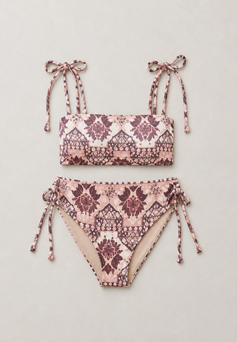 coral secret two-piece bikini set with a pink, beige, and dark purple geometric pattern, featuring tie straps on the top and sides on the bottoms, laid flat on a light beige background.