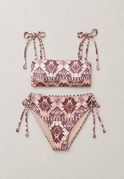 coral secret two-piece bikini set with a pink, beige, and dark purple geometric pattern, featuring tie straps on the top and sides on the bottoms, laid flat on a light beige background.