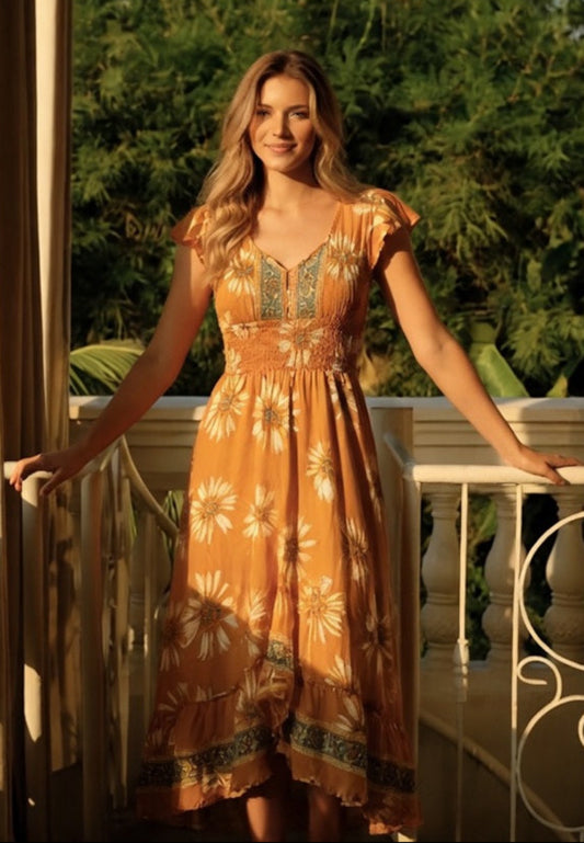 Woman in a floral dress standing on a balcony with greenery in the background