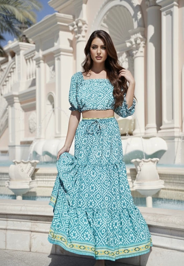 Woman in a blue patterned outfit standing in front of an architectural building with columns.