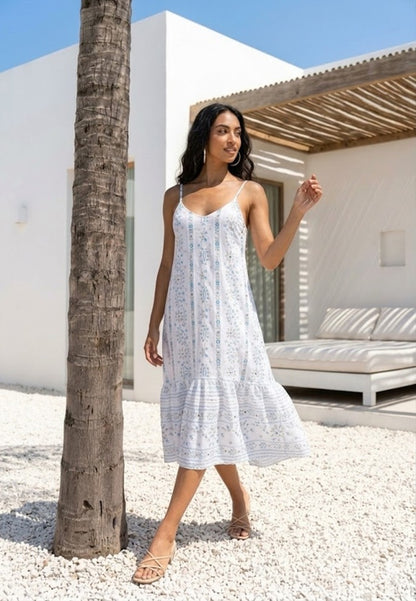 Woman in a white dress standing next to a palm tree in a sunlit outdoor setting