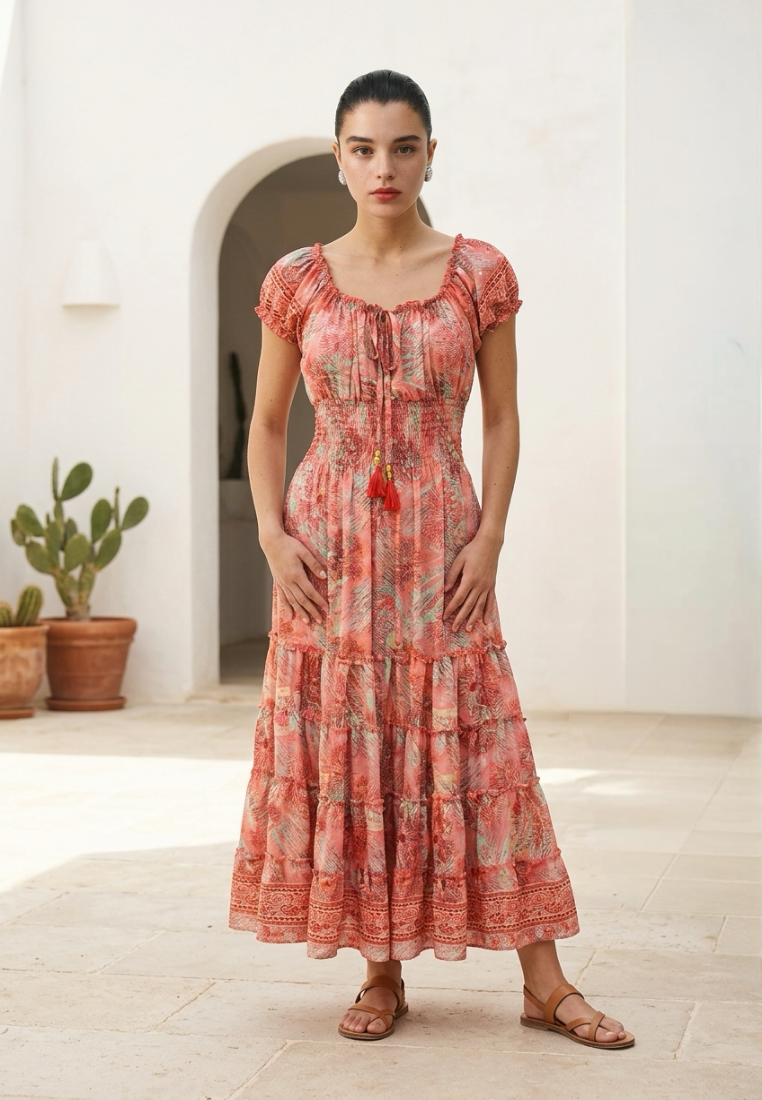 Woman wearing a pink floral dress standing in a sunlit room with plants.